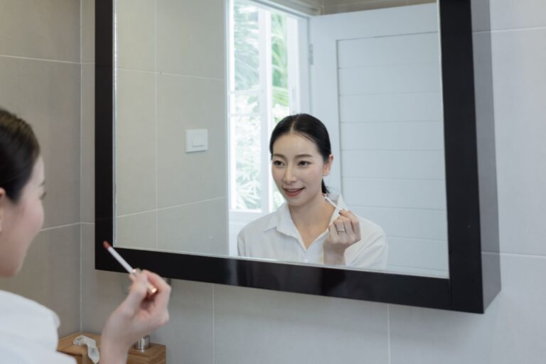 a woman applying makeup using a mirror