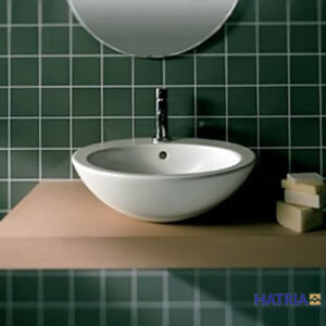 a basin in a bathroom with green tiled wall